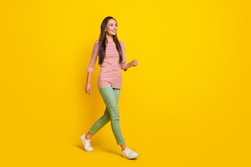 Fototapeta na wymiar Photo of funky sweet mature lady dressed striped shirt looking empty space walking smiling isolated yellow color background