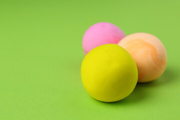 Different color play dough balls on light green background, closeup. Space for text