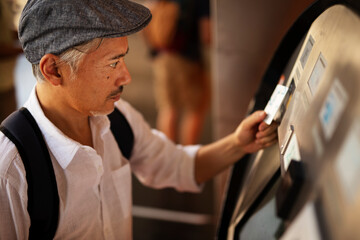 Naklejka na ściany i meble Senior man withdrawing money from credit card. Man typing pin code on keypad of ATM mashine