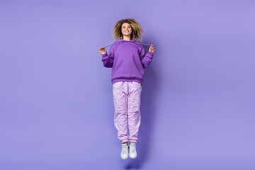 Photo of dreamy adorable lady dressed hoodie arms adjusting hood humping high isolated purple color...