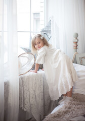 Fototapeta na wymiar Little cute girl near the window in her bedroom. Winter holidays, vintage style.