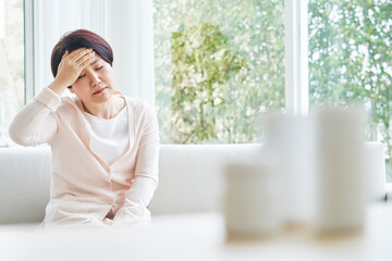 Middle-aged woman suffering from a headache while sitting on the sofa in the living room at home