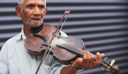 Partial close up photo of a senior man with pensive facial expression performing a melody using a...