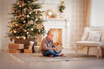 a child opens a gift under a Christmas tree
