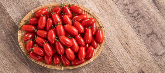Fresh cherry tomatoes over wooden table background.