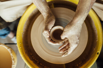 Hands of a potter. Potter making ceramic pot on the pottery wheel