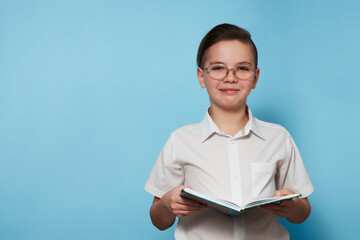 Obraz premium Portrait school boy with a book over blue background