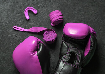 Pink boxing gloves with bandages and mouth guard. Breast cancer control concept. Black background