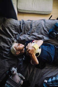 Directly above shot of boy contemplating while lying down in bedroom