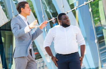 Finance, business and cooperation concept. Two successful businessmen are talking on the street. Office workers are discussing business issues outdoor.