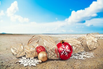 Christmas toys - colored balls on the beach, blurred sea in the background. New Year or Christmas card,