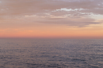 Naklejka na ściany i meble Orange and tan colors sunset sky over the sea. 