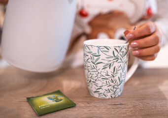 Fototapeta na wymiar Young woman's hands with a cup of herbal tea, in time of cold and wellbeing