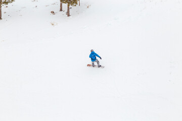 snowboarder is jumping with snowboard from snowhill. Skier skiing downhill in high mountains....