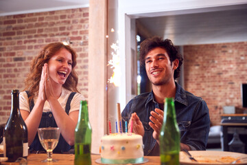 Multi-Cultural Group Of Friends Celebrating Birthday With Party And Cake At Home Together