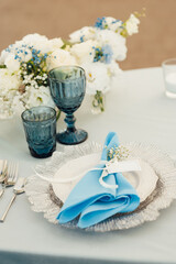 Wedding tables for guests with a blue tablecloth. Decorated with premium glasses and flowers