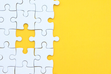 White puzzle pieces on yellow background, copy space for text.
