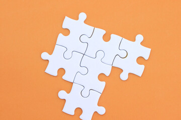 White puzzle pieces on orange background, copy space for text.