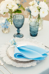 Wedding tables for guests with a blue tablecloth. Decorated with premium glasses and flowers