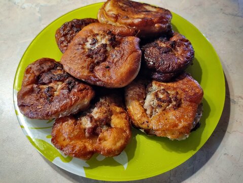 Fried dough with meat on a green plate. Food on the table. Close-up photo of a culinary. Belarusian belyashi.
