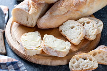 Fresh french baguettes with butter on a gray stone surface