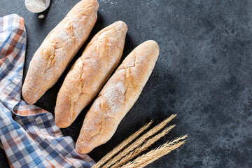 Fresh Baguette Bread on dark background. Homemade french Baguette loafs, top view, copy space.