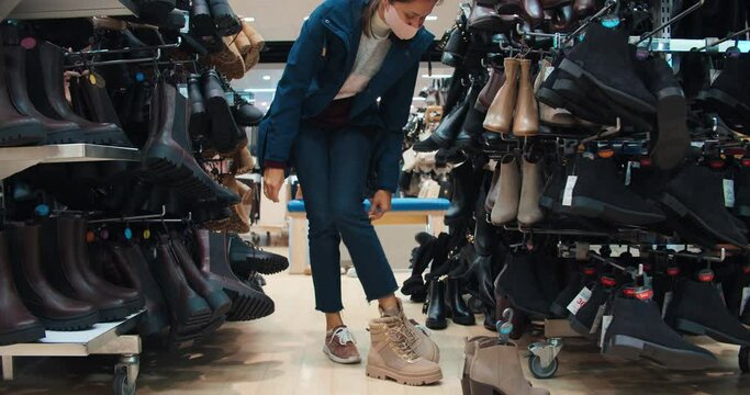 young woman legs trying new boots during shopping in commercial centre. Concept of buying new clothes and shoes