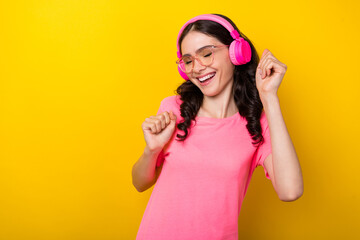 Obraz na płótnie Canvas Photo of young excited charming lady good mood dancing listen radio earphones isolated over yellow color background