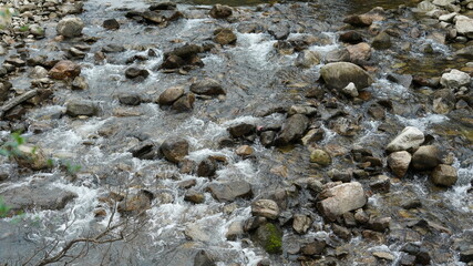 The river view with the water running over stones and rocks in the valley of the mountains