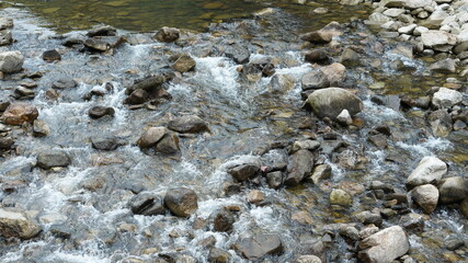 The river view with the water running over stones and rocks in the valley of the mountains