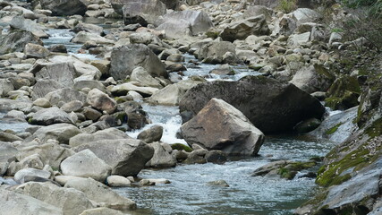 The river view with the water running over stones and rocks in the valley of the mountains
