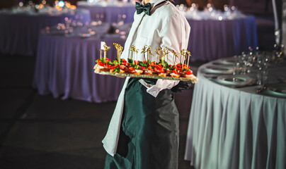 waiter holds tray with canape. Restaurant service. buffet or catering.