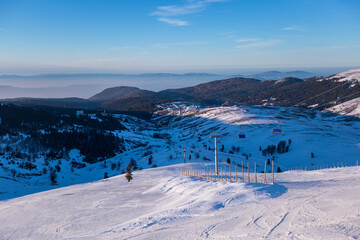 Ski slopes and Ski lifts. Small pine trees with snow. Mountain skiing and snowboarding. View of Erzurum city from Palandoken mountain