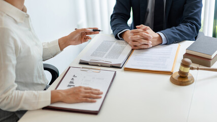 law concept The man in dark blue suit, a lawyer, sitting at his desk and trying to prepare to give law consultation to his customer with his assistance, the man in white shirt