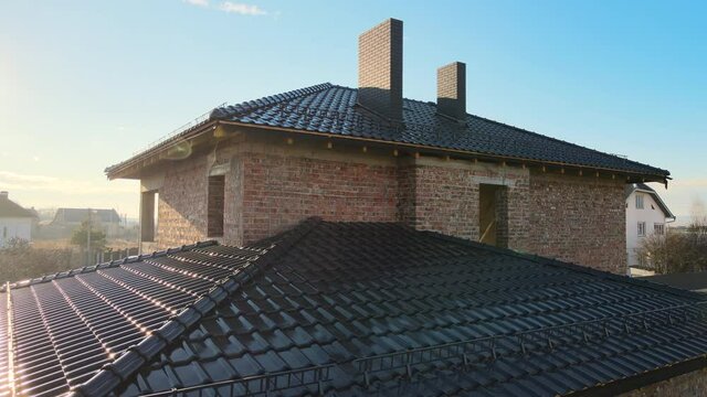 Closeup snow guard for safety in winter on house roof top covered with ceramic shingles. Tiled covering of building