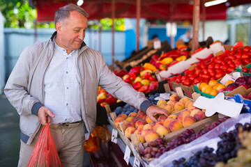Man choosing peaches in market