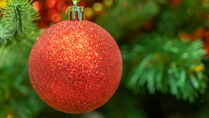 A red Christmas ball on a Christmas tree with a blurred background. Christmas and New Year decoration.