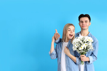 Cute couple with bouquet on blue background