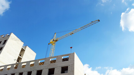 yellow construction crane and new high building and blue sky