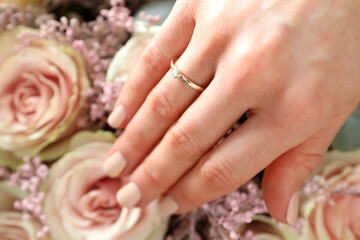 Female hand with wedding ring on wedding bouquet background