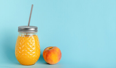 Peach smoothie jar with reusable metal drinking straw on blue background. Copy space