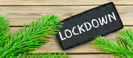 Schild mit Lockdown und Tannenzweigen auf Holz
