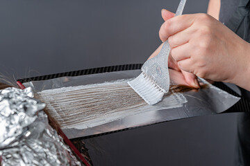 Process of applying bleaching powder on clients hair and wrapping into the foil. Shatush technique