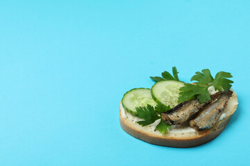 Tasty sandwich with sprats on blue background