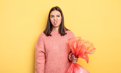 pretty woman feeling disgusted and irritated and tongue out. trash bag concept