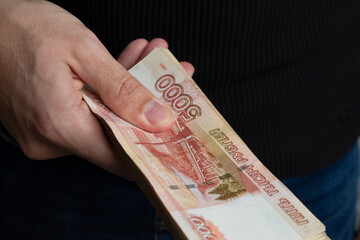 A man gives a wad of Russian money in five-thousand-dollar bills