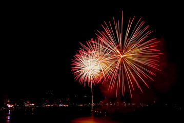 Spectacular red and gold fireworks exploding in to the night sky over the bay