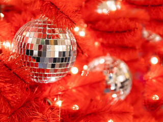 Red artificial Christmas tree with mirror disco balls. Bright fir tree decorated with light bulbs...
