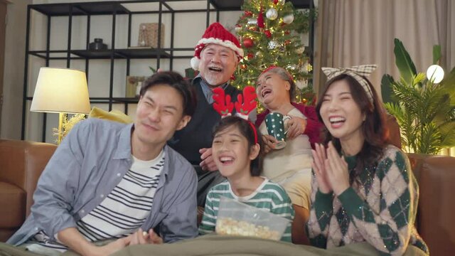 happiness asian family spending joyful festive time moment together at home,multi generation family grandparent parent and child watching comedy movie together  in christmas time at home 