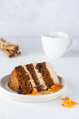 A piece of carrot cake with coconut cream and a cup of tea on a light background. Sugar, gluten and lactose free and vegan.